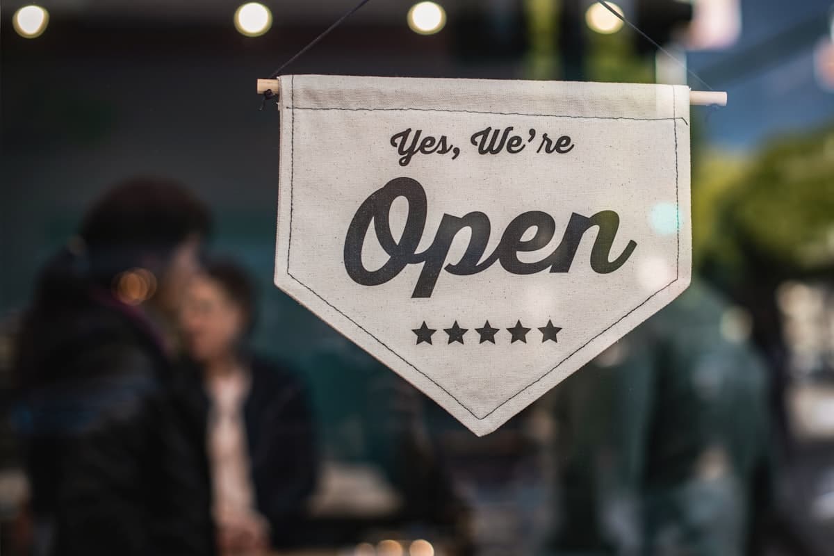 A canvas banner in a shop window that reads 'Yes, We're Open'