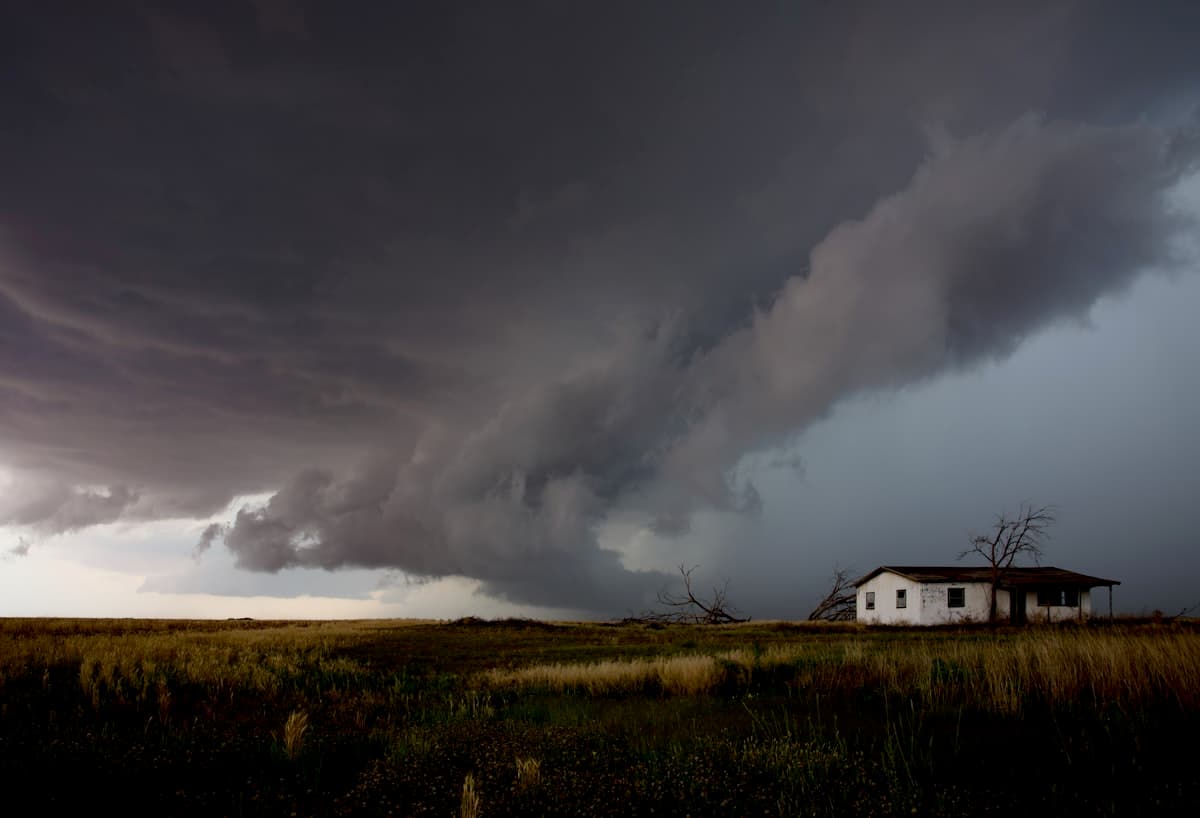 A storm front rolling across the open Texas landscape toward a small house